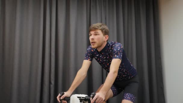 Sportowiec jeżdżący na rowerze na inteligentnym rowerze. Zbliżenie młodego chłopca pedałującego na rowerze w domu. Koncepcja wirtualnego roweru w pomieszczeniach — Wideo stockowe