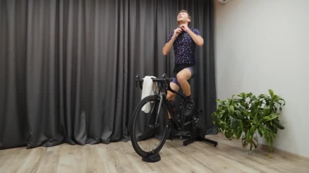 Ciclismo treino indoor no treinador inteligente. Sudorese masculina enquanto treina de bicicleta, desabotoando camisa e segurando toalha. Ciclismo conceito virtual — Vídeo de Stock