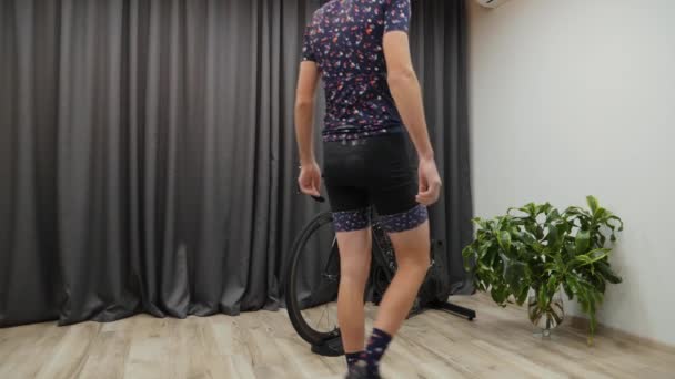 Man starts to cycling indoor on smart trainer. Male training on bicycle trainer. Indoor Virtual Cycling concept — Stock Video