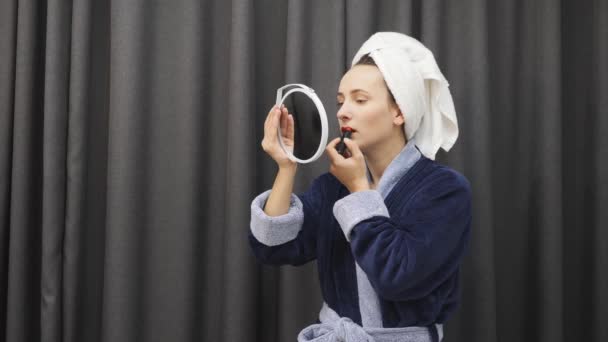 Woman painting lips with red lipstick. Girl doing bright makeup. Female in bathrobe applying lipstick. Beautiful makeup. Health and beauty — 비디오