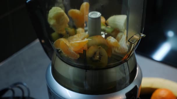 Cutted fruits in blender on kitchen. Preparing fruits smoothie, close up. Mix of fruits in mixer. Fresh fruits juice cooking process. Detox beverages. — Stock Video
