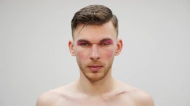 Kameraya bakan mütevazı bir travesti. Parlak makyajlı transseksüelin ön görüntüsünü kapatın. Gülünç bir kavram. Makyajlı bir adam portresi.