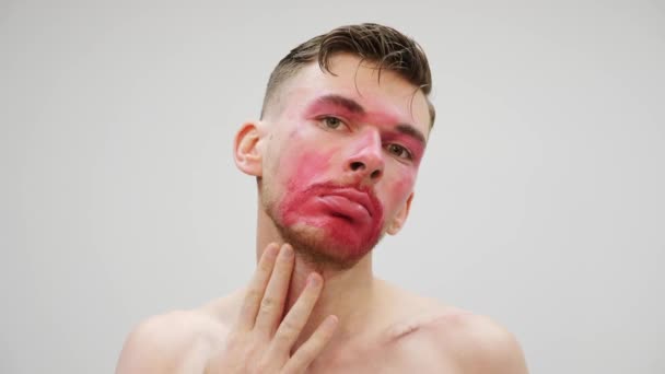 Een man die make-up op z 'n gezicht smeert. Travestie man verwijdert cosmetica uit het gezicht. Portret van transseksuele vlekken make-up. Travestie en transseksueel concept — Stockvideo