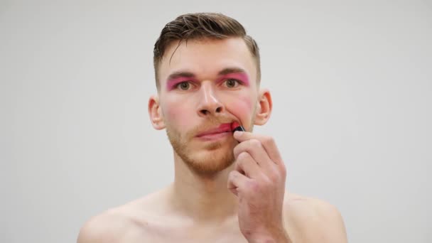 Travestie man die lippenstift op de lippen aanbrengt. Een man die make-up op z 'n gezicht smeert. Portret van transseksuele man brengt roze lippenstift en smeer cosmetica op het gezicht. Transseksueel en travestie concept — Stockvideo