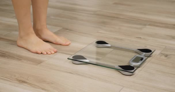 Human barefoot steps on body weight scales. Woman checking weight on scale in room. Girl measuring overweight — Stock Video