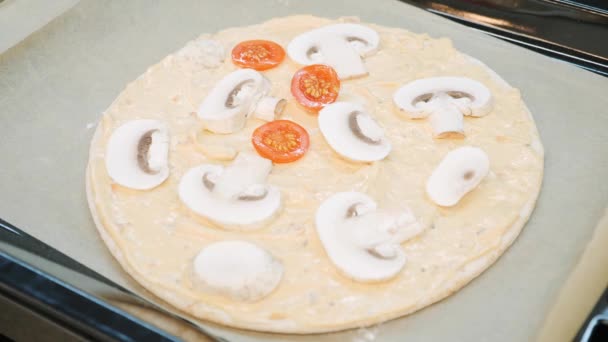 Honan tillsätter tomater till pizzabasen. Kocken lagar pizza. Kvinna som tillsätter ingredienser till italiensk pizza. Beredning av grönsakspizza. — Stockvideo