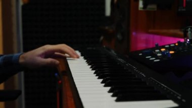 Erkek eller ev müziği stüdyosunda piyano midi klavye çalıyor. Ses yapımcısı stüdyoda pop rock şarkıları yaratıyor. Elektronik piyanoda çalan elleri kapatın. Kadın parmaklar müzik stüdyosunda piyano çalıyor.