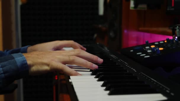 Ujjak zongoráznak midi billentyűzeten a stúdióban. A kezek zongoráznak és dalokat készítenek a digitális audió munkaállomáson. Zeneszerzési folyamat. Zongora billentyűzeten játszó zenész — Stock videók