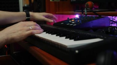 Ses mühendisi ev müzik stüdyosunda dengeleyici miksaj ekipmanlarıyla çalışıyor. Kayıt stüdyosunda erkek eller elektrikli piyano çalıyor. Müzik mühendisi pop rock şarkılarını karıştırıyor ve ustalaştırıyor