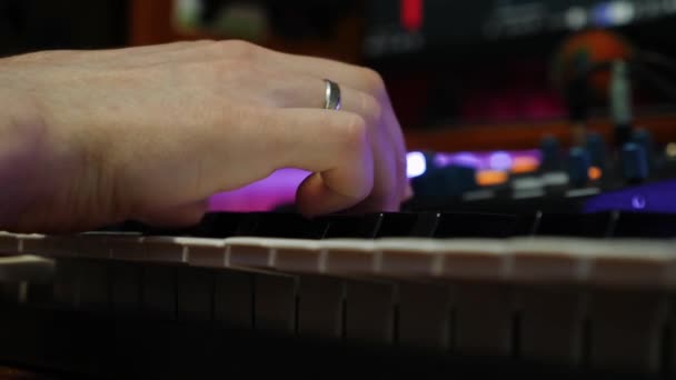 家庭用スタジオでエレキピアノを弾いている男性の指。手を閉じるピアノミディキーボードを再生します。ホームスタジオで音楽制作を行うサウンドエンジニア。作曲プロセス — ストック動画