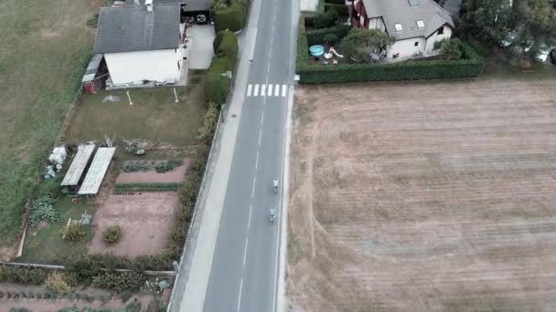 Homens de bicicleta andando na comuna de Doussard, França, montanhas dos Alpes. Drone vista de turistas ciclismo através de campos — Vídeo de Stock