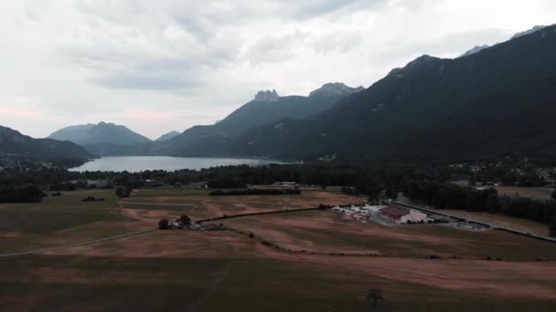 Valle de la montaña con lago y campo, comuna de Doussard, Francia. Vista de drones de los Alpes. Montañas fondo — Vídeo de stock