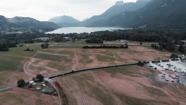 Dron letící mezi horským údolím s jezerem a polem. Annecy Lake v obci Doussard, Francie. Alpské hory pozadí — Stock video