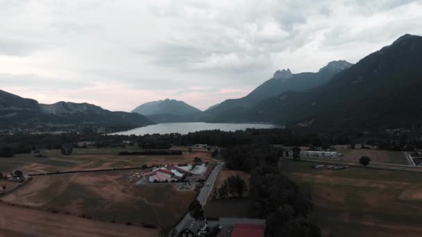 Bovenaanzicht vanuit de lucht op velden omringd door Alpbergen. Lake Annecy in gemeente Doussard, Frankrijk. Berg vallei, drone schot uitzicht — Stockvideo