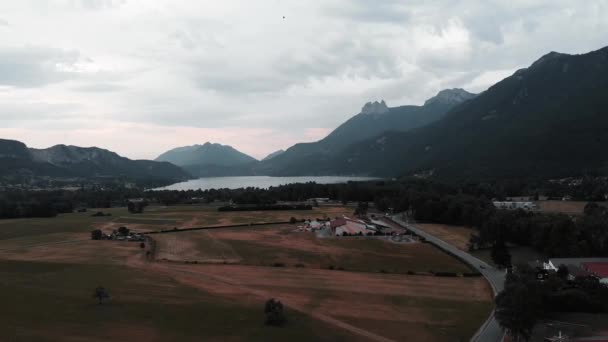 Montañas alpinas con centro de parapente en la parte delantera, vista al dron. Vista aérea del hermoso lago de montaña en la comuna de Doussard, Francia — Vídeo de stock