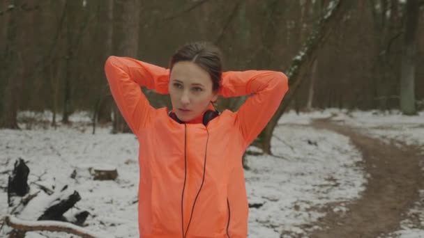 Frau bindet Schwanz. Weibchen binden den Schwanz im Park vor dem Lauftraining im Freien. Profisportler bereiten sich im Winterwald auf das Lauftraining vor. Trailrun-Konzept — Stockvideo