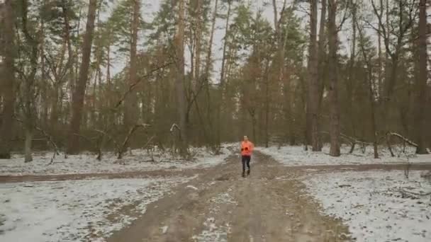 Женщина бегает в парке. Молодая мотивированная женщина бегает в зимнем лесу. Профессиональный спортсмен в спортивной одежде тренируется на открытом воздухе. Женщина делает интенсивные упражнения в межсезонье. Следы бегут. Активный спорт — стоковое видео