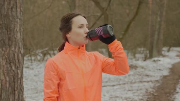 Zmęczona i spocona kobieta pije wodę po bieganiu. Kobiety pijące izotoniczne z butelki po treningu. Młody słodkie sportowe dziewczyna połykanie wody po ciężkim treningu i przywrócenie równowagi wody — Wideo stockowe