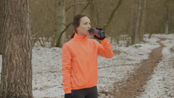 Młoda kobieta pijąca wodę w parku. Atrakcyjne słodkie kobiety pijące izotoniczne z butelki po ciężkim treningu. Dziewczyna przywracając równowagę wodną po bieganiu na zewnątrz. Sportowiec pije wodę po treningu — Wideo stockowe
