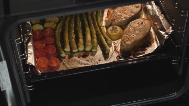 Mulher a preparar o jantar fora do forno. Peixe cozido e legumes em forno elétrico. Bife de salmão assado na cozinha. Chef de restaurante cozinhado deliciosa truta com guarnição — Vídeo de Stock