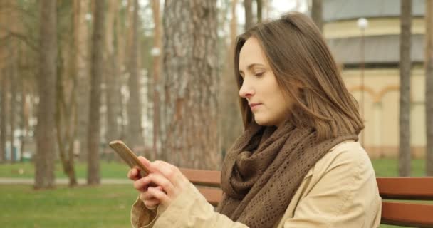 Giovane donna che tiene il cellulare e scorre e scorre i social network sorridendo e ridendo godendo della sua vita sociale. Concetto di vita Internet — Video Stock