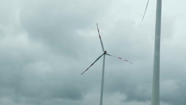 风车在灰蒙蒙的天空下转弯. 风力涡轮机产生清洁的可再生能源。 使用清洁和可再生能源的能源生产。 风车农场 — 图库视频影像