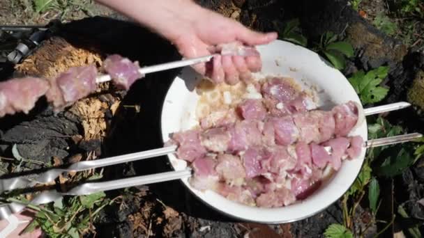 Человек прилипает сырое мясо к шампуру. Готовлю мясо на гриле. Барбекю на открытом воздухе. Процесс приготовления жареного мяса — стоковое видео