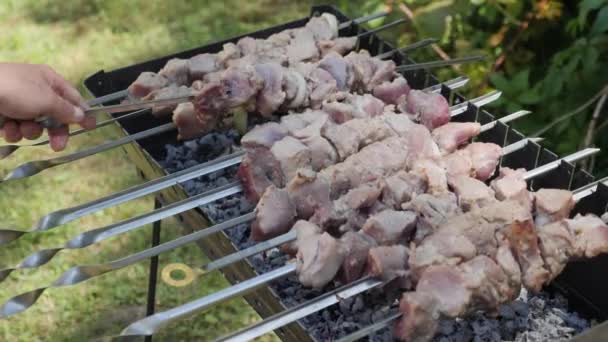 Raw meat on skewer, close up view. Meat pieces on grill. Barbecue outdoor. Preparing food process. Man flips pickled meat — Stock Video
