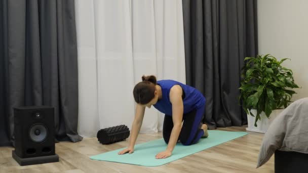 Fit sportieve brunette in yoga positie thuis. Geconcentreerde vrouw die yoga oefeningen beoefent in een heldere kamer. Gericht ontspannen vrouw doen stretching training op mat thuis. Vrouw strekt spieren uit — Stockvideo