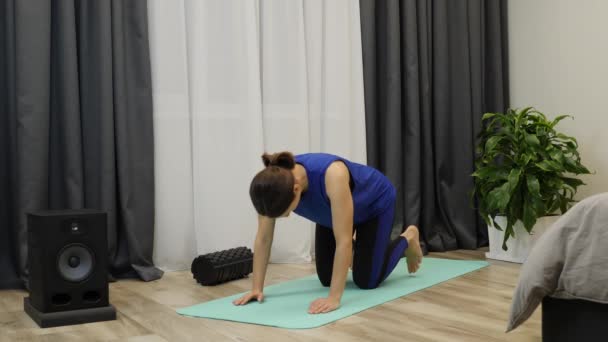 Fit sportieve brunette in yoga positie thuis. Geconcentreerde vrouw die yoga oefeningen beoefent in een heldere kamer. Gericht ontspannen vrouw doen stretching training op mat thuis. Langzame beweging — Stockvideo
