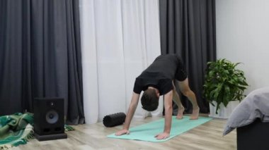 Sportif adam yoga pozu veriyor. Genç erkek yoga minderinde pratik yapıyor. Erkek jimnastikçi evde meditasyon egzersizleri yapıyor. Spor yapan bir sporcu. Sağlık hizmetleri kavramı