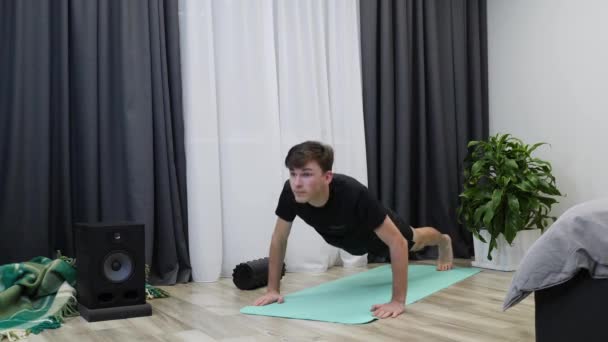 Människan gör armhävningar. Ung manlig idrottsman gör push-up övningar på yogamattan. Fitness instruktör visar armhävningsträning. Boy öva fitness lektioner och göra träning övningar — Stockvideo