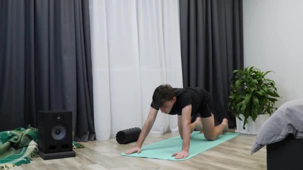 Människan nosar upp yogapositionen på mattan. Ung koncentrerad manlig träning i yoga hemma. Passar stilig pojke som tränar yoga och fitness. Idrottare som stretchar inomhus. En hälsosam livsstil — Stockvideo