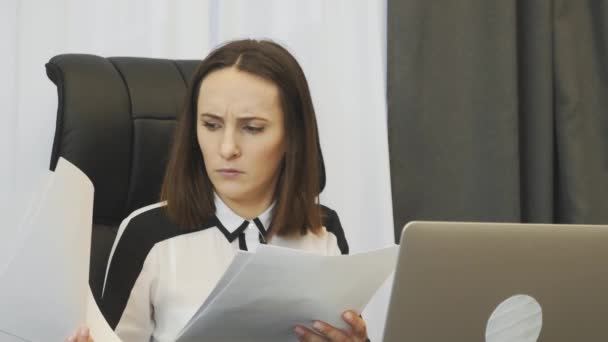 Shocked female boss looking at financial report. Worried businesswoman looks at company accounts. Upset woman watching at reports and worries about situation on financial stock market — ストック動画