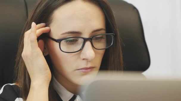 Ritratto di donna concentrata che lavora su laptop in ufficio. Primo piano della donna d'affari che guarda sul monitor del computer portatile. La femmina sicura in occhiali guarda lo schermo di computer. La faccia di donna lavora in ufficio su computer portatile — Video Stock