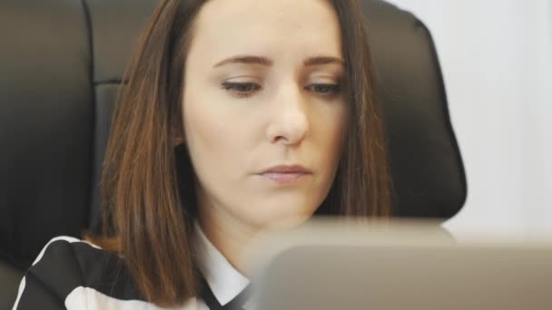 Mujer enfocada se pone anteojos antes de trabajar en el portátil. Primer plano de la cara femenina mirando en la pantalla del ordenador portátil. Retrato de una empresaria confiada trabajando en un portátil en su escritorio. Concepto de éxito empresarial — Vídeos de Stock
