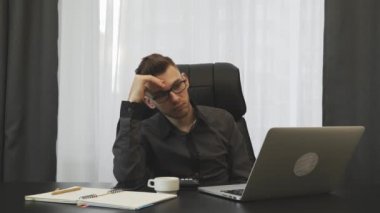 Ofiste dizüstü bilgisayara bakan üzgün bir adam. Kafkasyalı genç işadamı modern ofiste çalışıyor. İnternetteki kötü haberlerden mutsuz bir erkek. Bilgisayar ekranında kötü haber okuyan adam ofisinde oturuyor.