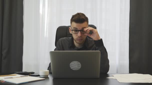 Бизнесмен устал на работе. Человек в костюме снимает очки и массирует глаза после тяжелого рабочего дня на рабочем месте. Мужчина-трейдер перетрудился в офисе. Сотрудник снимает очки после работы — стоковое видео