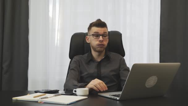 El hombre que trabaja en el portátil en la oficina moderna. Empresario cansado después de horas extras de trabajo en la oficina en la computadora. Hombre trabajando solo en teclado portátil. El corredor masculino se quita las gafas. Concepto empresarial — Vídeo de stock