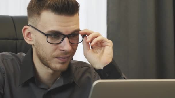 Biznesmen czyta wiadomości w internecie, zamyka. Portret mężczyzny zakłada okulary i patrzy na ekran laptopa. Pracownik pracujący na komputerze. Close up widok człowieka w okularach czytanie wiadomości na laptopie — Wideo stockowe