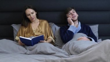 Kadın ve erkek uyumadan önce yatakta yatıyorlar. Genç bir çift yatak odasında yatıyor. Kitap okuyan bir kadın ve yatakta telefonla konuşan bir erkek. Genç evli çift yatakta dinleniyor. Romantik ilişki