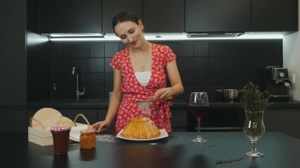 Chica cocinó pastel casero en la cocina casera moderna. Sonriendo feliz ama de casa preparado pastel horneado. Mujer joven caucásica en vestido rojo en la cocina profesional. Cocinera horneada pastel de Navidad — Vídeo de stock