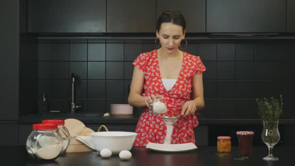 Menina feliz adulto cozinhar na cozinha moderna. Retrato de mulher jovem na cozinha doméstica profissional. Fêmea atraente peneira farinha na cozinha e bolo cozido. feliz dona de casa preparar caseiro torta — Vídeo de Stock