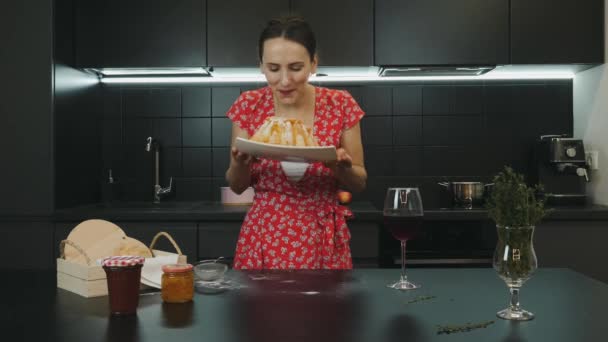 Счастливая улыбающаяся женщина с приготовленным пирогом на современной профессиональной кухне. Молодая привлекательная домохозяйка испекла домашний торт. Портрет женщины на домашней кухне. Концепция здорового питания — стоковое видео