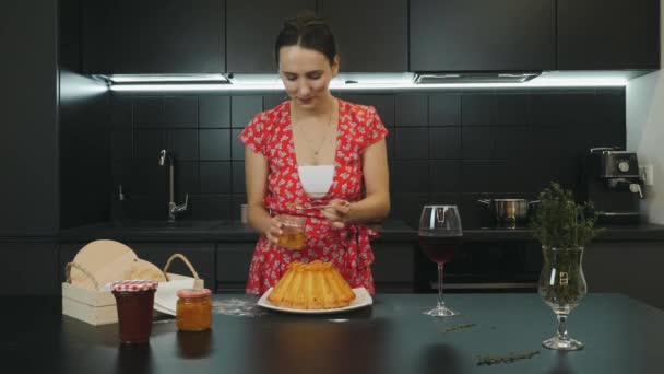 Happy girl decorating baked pie with fruit. Young smiling woman decorates baked homemade cake in modern professional kitchen. Portrait of attractive female is cooking in home kitchen. Food concept — Stock Video