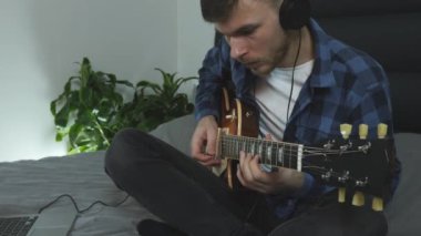 Elektro gitarla çalan profesyonel gitar öğretmeni. Kulaklıklı genç adam yeni şarkı sözlerini söylüyor. Gitar çalan erkek gitarist. Müzisyen yeni akorlar öğreniyor. Gitar dersleri. Müzik konsepti