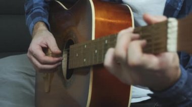 Erkek eli akustik gitarda oynuyor. Akustik gitar tellerini tıngırdatan parmaklar. Kapat.