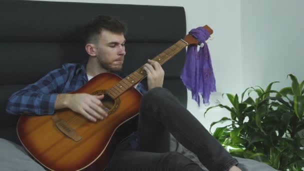 Zene zeneszerző ír egy dalt otthon ül az ágyán kezében egy akusztikus gitár. Zenei koncepció — Stock videók