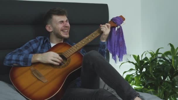 若い髭の男がアコースティックギターで演奏し、一緒に歌っている。アコースティックギターを弾いている間の感情的な歌. — ストック動画