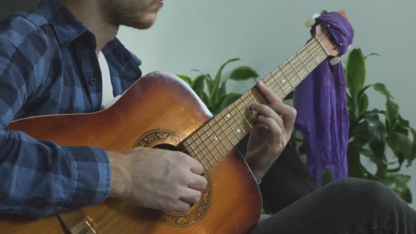 Fiatal dalszerző, aki otthon komponál egy dalt. A férfi játszik a régi akusztikus gitár szvingelés és szedés húrok és a változó akkordok. — Stock videók